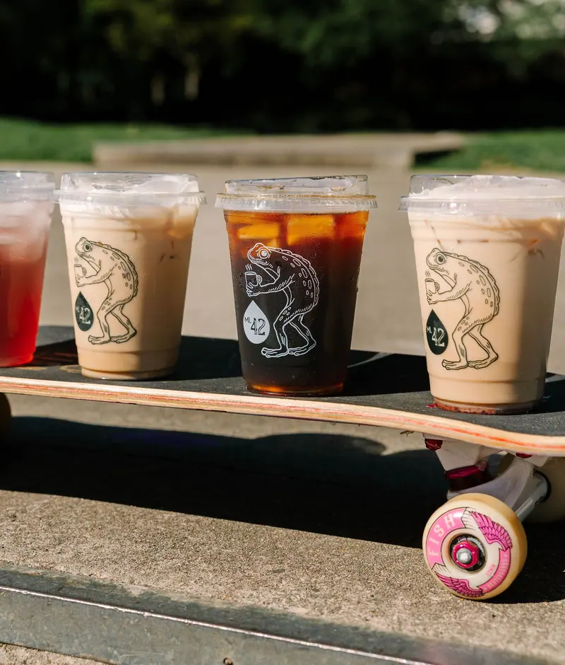 Four Mile 42 iced drinks in Frogman cups lined up on a skateboard
